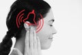 Tinnitus. A dissatisfied young woman holds her hand over her ears, experiencing ringing and pain. The concept of ear