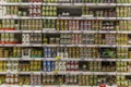 Tins of canned food on the shelves in the supermarket. Big choice. Front view. Blurred