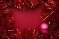 Tinsel with ball on red background. Space for text Royalty Free Stock Photo