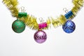 Tinsel with pinned christmas ornaments, white background, copy space. Balls with ornaments hang on shimmering golden Royalty Free Stock Photo