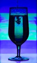 Tinted glass of champagne with splashes of liquid on abstract blurred background. Royalty Free Stock Photo