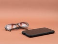 Tinted glasses and mobile phone on a brown background. Royalty Free Stock Photo