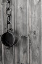 Tinted gray closed iron shackles closed with chain hanging on wooden background Royalty Free Stock Photo