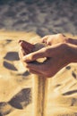 Tinted image sand pours out of the female hands