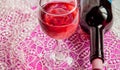 Tinted pink effect - a Glass of wine and a bottle on a lace tablecloth. Top view, flat lay