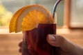 Tinto de verano, man holding an alcoholic red wine mixed drink with orange garnish in hand, drinking, metal straw Royalty Free Stock Photo