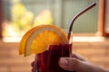 Tinto de verano, man holding an alcoholic red wine mixed drink with orange garnish in hand, drinking, metal straw Royalty Free Stock Photo