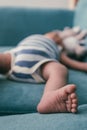 Tiny baby foot on a sleeping baby on a green sofa