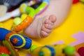 Tiny baby's foot among toys