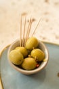 A Tiny Bowl of Whole Green Olives and Some Toothpicks