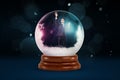 A tiny businessman inside a snowy crystal ball on a dark background with flecks of snow falling.