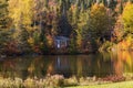 Tiny cabin nestled in colourful fall foliage at the edge of a small lake