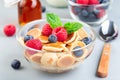 Tiny cereal pancakes served with maple syrup, raspberry, blueberry and milk, in a glass bowl, horizontal Royalty Free Stock Photo