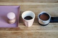 Tiny coffee pink ceramic cup, macarons, coffee holder on wooden table or background. Royalty Free Stock Photo