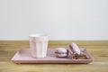 Tiny coffee pink ceramic cup and macarons on wooden table or background, white wall behind Royalty Free Stock Photo