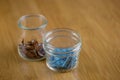 Tiny colorful pins in glass jars in macro with wooden background
