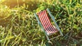 Tiny colorful toy deckchair in grass. Summer vacation concept. Sunset time. Children dreaming of holiday rest. Small toy on lawn. Royalty Free Stock Photo