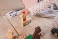 Tiny colorful wooden toy shapes and building blocks on hardwood floor.Girl play with a wooden set in their children`s Royalty Free Stock Photo