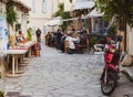 Tiny cute Greek street with people enjoying food street restaurant