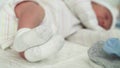 Tiny Cute Newborn Babies Feet In Socks Early First Days Of Life On White Background. Close up of Small Legs of Infirm