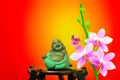 Tiny figurine of laughing buddha and pink orchid flowers Royalty Free Stock Photo