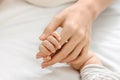 Tiny fingers of newborn baby holding mother`s hand, closeup