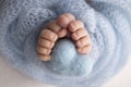 The tiny foot of a newborn baby. Close up of toes, heels and feet of a newborn. Knitted blue heart in the legs of a baby