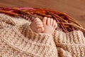 Tiny foot of newborn baby. Soft newborn baby feet against a beige blanket. Baby feet with toes curled up