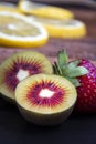 Tiny fruits, green and red kiwis, and a red ripe strawberry.