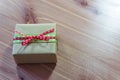 Tiny gift box wrapped in rustic brown kraft paper with red and green ribbons, simple bow Royalty Free Stock Photo