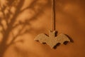Tiny handmade bat of recycled paper hangs from jute string against warm clay wall. Blurred tree shadow and golden light create Royalty Free Stock Photo