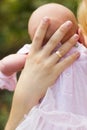 Tiny head of newborn baby girl wearing pink dress on hands of her mother Royalty Free Stock Photo