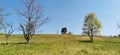 Lonely abandoned tiny house on summer time grassy hilltop with clear blue sky