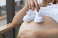 tiny knitted booties for newborns in the hands of a pregnant woman, waiting for the baby, enjoying the pregnancy Royalty Free Stock Photo