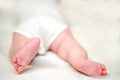 Tiny legs of a baby in a white bodysuit. An admiring innocent girl lying in a comfortable crib in the bedroom Royalty Free Stock Photo