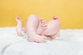 Tiny legs of a baby in a white bodysuit. An admiring innocent girl lying in a comfortable crib in the bedroom Royalty Free Stock Photo