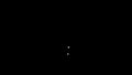 Tiny light particles rising up in the dark. Design. Small flying white dots on a black background, seamless loop