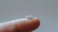 Tiny microchip on tip of human finger, on pale grey background. Copy space. Macro. Royalty Free Stock Photo
