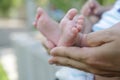 Tiny newborn baby foot in his mother`s palm in warm colors in soft focus background. Hands of mother and baby foot. Royalty Free Stock Photo