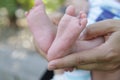 Tiny newborn baby foot in his mother`s palm in warm colors in soft focus background. Hands of mother and baby foot. Royalty Free Stock Photo