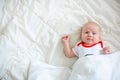 A tiny newborn baby on a huge bed under a white blanket. Emotions of a newborn baby. A little girl saw her mother. Royalty Free Stock Photo