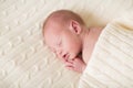 Tiny newborn baby sleeping on soft knitted blanket