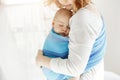 Tiny newborn child close eyes and having good sleep in baby sling feeling protection from his beautiful young mother Royalty Free Stock Photo