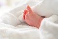 Tiny newborn foot peeking out after bath beneath soft white towel