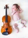 Tiny newborn girl lying next to a violin