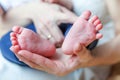 Tiny newborn infant male or female baby feet and toes on mother hand Royalty Free Stock Photo