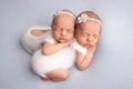 Tiny newborn twin girls. A newborn twin embraces and sleeps on his sister, Newborn twin girls against pale blue blanket Royalty Free Stock Photo