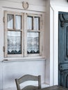 tiny old style vintage house facade with a wooden door and creamy color window with white embroidered curtains, aegean and Royalty Free Stock Photo