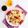 Tiny pancakes with berries, honey, coffee. Pancake cereal. The concept of Breakfast, food trends. Copy space