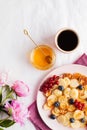 Tiny pancakes with berries, honey, flowers, coffee. Pancake cereal. The concept of Breakfast, food trends. Copy space